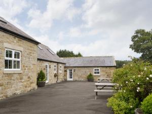 Grooms Cottage في Elsdon: عمارتين فيها مقاعد