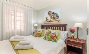 a bedroom with a large white bed with green pillows at A Whale of a Time Knysna in Knysna