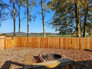 a backyard with a fire pit in front of a wooden fence at Gallowhill Kirkside - Uk46515 in Newmill