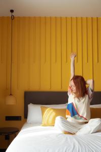 een vrouw zittend op een bed met haar hand in de lucht bij BYPILLOW Crosstown in Madrid