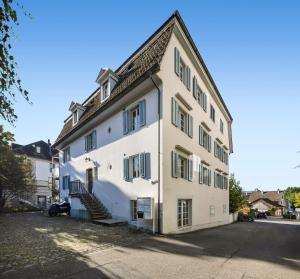 a white building with stairs on the side of it at Spacious light-flooded apartment with garden at Lake Zurich in Männedorf