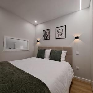 une chambre avec un grand lit blanc avec des oreillers verts dans l'établissement Alameda Apartments 2, à Trofa
