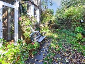 Un banco sentado afuera de una casa con hojas. en Sunnycote, en Arnside