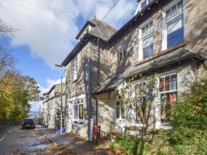 una vieja casa de piedra al lado de una calle en Sunnycote, en Arnside