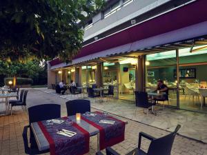 Un restaurante con mesas y sillas y gente sentada en las mesas. en Mercure Brive, en Ussac