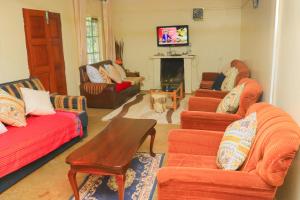 a living room with orange couches and a fireplace at Nancy's Farm House in Chuka