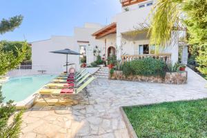 una casa con piscina con panchina e ombrellone di Villa Juan by Villa Plus a Portopetro