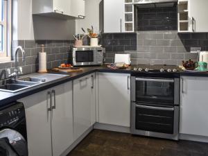 een keuken met witte kasten en zwarte apparaten bij The Dairy - Uk50885 in North Walsham