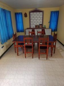 uma sala de jantar com mesa e cadeiras e cortinas azuis em Sunshine Royale em Kodaikānāl