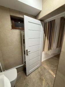 ein Badezimmer mit einer weißen Tür und einem WC in der Unterkunft Casa Cota in Craiova