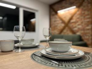 a wooden table with two plates and wine glasses at Pod Palmami in Hel