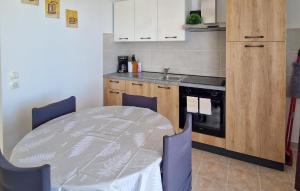 Stunning Apartment In Rab في Barbat na Rabu: مطبخ مع طاولة وكراسي ومغسلة