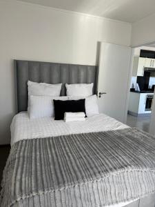un grande letto con testiera grigia in una camera da letto di SkyAre Windhoek CBD a Windhoek