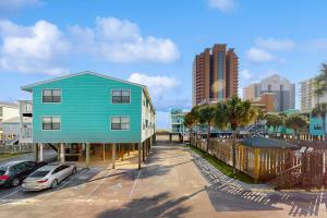 ein blaues Haus neben einem Parkplatz mit Autos in der Unterkunft Lani Kai 123 in Gulf Shores