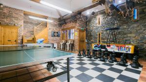a ping pong table in a room with a stone wall at Llydaw in Pwllheli