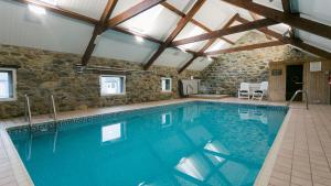 a large swimming pool in a house with a stone wall at Llydaw in Pwllheli