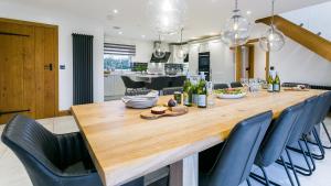 a dining room and kitchen with a large wooden table and chairs at Llydaw in Pwllheli