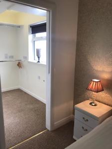 a bedroom with a bed and a lamp on a dresser at The Downtown Loft in Buncrana