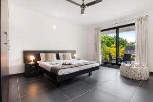 a bedroom with a bed and a large window at Crystal Village in Nagoa-Bardez