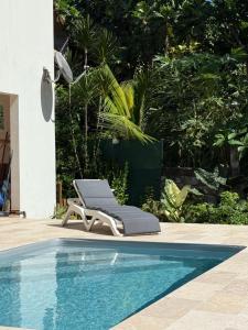 a lounge chair sitting next to a swimming pool at Ti Bwa Lodge, bas de villa cosy, piscine & vue mer in Capesterre-Belle-Eau