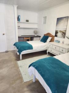 a bedroom with two beds with blue pillows and a desk at Hannah's Close in Struisbaai