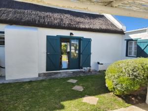 a white house with a blue door at Hannah's Close in Struisbaai