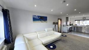 a living room with a white couch and a kitchen at Stepping Stones in Perranporth