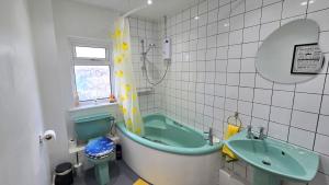 a bathroom with a green tub and a sink at Stepping Stones in Perranporth +17 photos