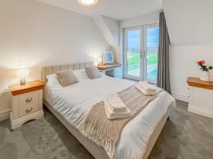 Un dormitorio con una gran cama blanca con ventana. en Eriska View, en Port Appin 13 fotos más