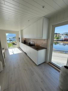 a kitchen with white cabinets and a large window at Aurora Bay Villa Lofoten 罗弗敦极光湾海景顶层别墅 in Sund