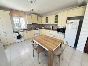a kitchen with a wooden table and white appliances at ALTINKUMDA 12 Kişilik ÖZEL HAVUZLU VİLLA in Didim