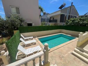 a swimming pool with two chairs next to a house at ALTINKUMDA 12 Kişilik ÖZEL HAVUZLU VİLLA in Didim