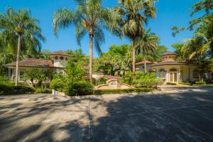 赫拉多拉Harmon Estate 6 bdrs private pool in Los Suenos的车道前有棕榈树的房子