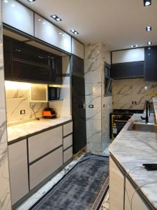 شقه مفروشه علي النيل فيو تحفه في ‘Ezbet el-Auqât: مطبخ مع أسطح عمل بيضاء وخزائن سوداء ومغسلة