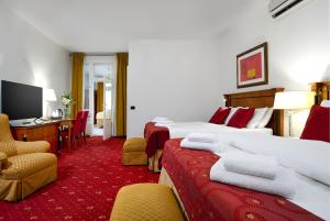 a hotel room with two beds and a desk at Hotel Leon D´Oro in Prague