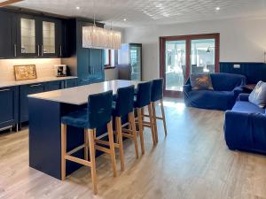 Una cocina con gabinetes azules y una mesa y sillas. en Abalone, en Culbokie