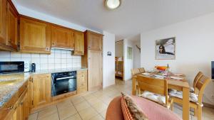a kitchen with wooden cabinets and a table and a dining room at Plein Ciel VA 032 - MOUNTAIN apartment 6 pers in Veysonnaz