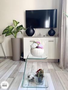 een woonkamer met een tv en een glazen tafel met bloemen bij Paty's House Milano in Milaan