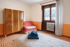 松达洛Appartamento Alice的一间卧室，里面有一张床、一把椅子和一扇窗户