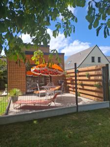 a fence with a table and chairs in a yard at Maisonnette Rétro Loc in Amfréville