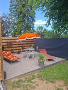 a patio with a table and chairs and an umbrella at Maisonnette Rétro Loc in Amfréville