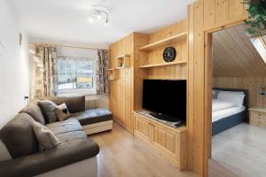 a living room with a couch and a tv and a bed at Appartamento Primavera 3 in Moena