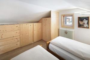 1 Schlafzimmer mit 2 Betten und Holzschränken in der Unterkunft Appartamento Primavera 3 in Moena