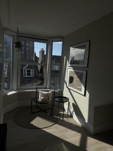 Park House Rooms - Sky TV and kitchenette في أبردين: غرفة مع طاولة وكرسي ونوافذ اثنين