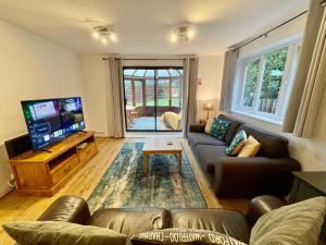 uma sala de estar com um sofá e uma TV de tela plana em Large 5 bed detached house near Stansted Airport with Parking for 2 vehicles! Stansted Stays em Stansted Mountfitchet