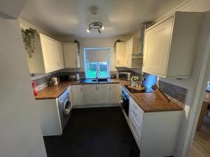 a kitchen with white cabinets and a sink at Glebeside House in Satley