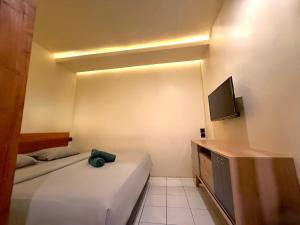 Una pequeña habitación con dos camas y un televisor. en Buton Backpacker Lodge, en Bandung