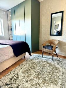 een slaapkamer met een bed, een stoel en een spiegel bij BB BEACH BAY QUALITY APARTMENTs in Cape Town +27 foto's