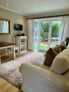 een woonkamer met een witte bank en een glazen schuifdeur bij BB BEACH BAY QUALITY APARTMENTs in Cape Town