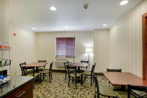 a dining room with tables and chairs and a kitchen at Cobblestone Inn & Suites - Clintonville in Clintonville